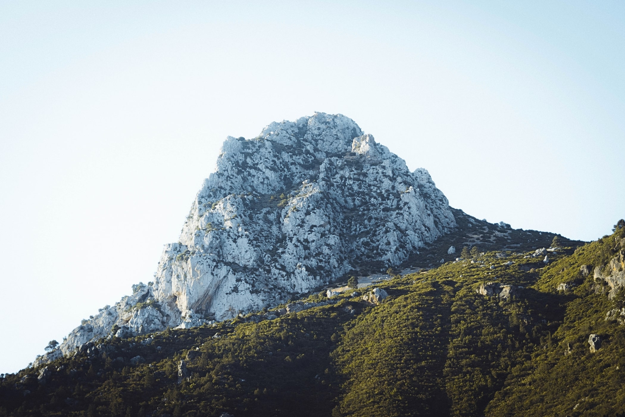 Marocco mountain peak rises above lush green hills at Banyan Tree Tamouda Bay, under a clear sky.